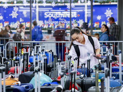 A woman searches for a suitcase in a baggage holding area for Southwest Airlines at Denver International Airport on December 28, 2022 in Denver, Colorado.