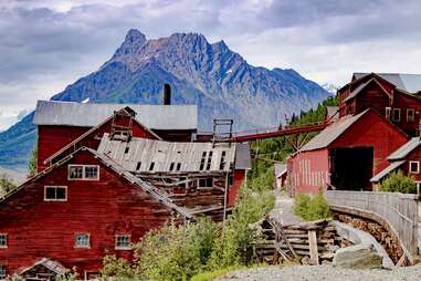 a rickety red mining town in front of a mountain