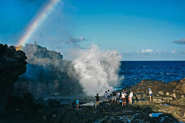 tourists surrounding a blowhole near the ocean