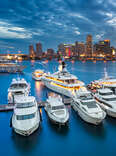 Miami skyline at dusk on cloudy evening with dramatic sky showing brickell and downtown and the marina in the foreground with the large impressive yachts and boats. 